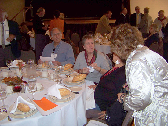 Seated and standing guests in conversationaround a luncheon table