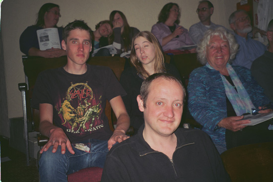several audience members look towards camera, awaiting the show to begin
