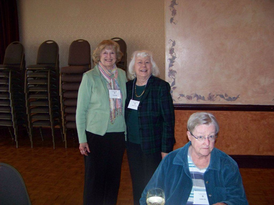 Two guests standing and one sitting at the 2013 Saint Patricks Day Luncheon looking at the camera